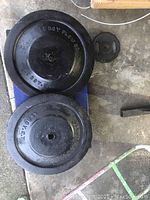 Top-down photo showing two heavy cast iron wheels side by side on a concrete floor, each with central mounting hole and visible 'LEROY PLOW CO' embossing.