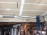 Full-length view of chrome barbell suspended from ceiling, showing entire 7 ft length
