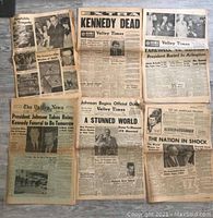Six old newspapers laid out flat. Headlines about JFK assassination and aftermath visible.