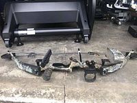 Full side view of the PSE Nova Compound Bow with camouflage limbs stretched on ground, showing bow design and accessories including arrow rest and quiver.