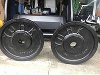Front view of two black York Olympic barbell weight plates on concrete floor.