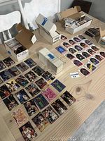 Wide shot of many basketball trading cards arranged on a table, showing multiple players and several stacks and open boxes.
