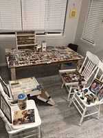 Wide view of a table and chairs filled with multiple sports trading cards, boxes and bobbleheads.