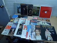 Overall view of a collection of 18 vinyl LP records, displaying front cover artwork for various artists and titles.