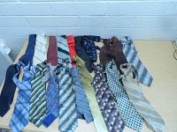 Wide top-down view of 16 men's neck ties laid out showing colors, patterns and textures.