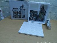 Village building and original styrofoam packaging with box showing an image of the building.