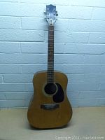 Full body of the dreadnought acoustic guitar showing natural wood finish, black pickguard, and general wear.