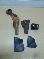 Top-down view of five leather gun accessories arranged on table surface.