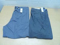 Two folded pairs of Polo Ralph Lauren dress pants on a table in shades of blue and gray.