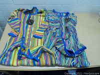 Two Bergati dresses laid flat showing colorful stripe patterns and blue trim, tags visible