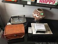 View of Panasonic DVD player, Sony clock radio, perforated ceramic lamp, and brown textured treasure box on black table.