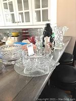 Multiple crystal bowls and a ceramic vase shown on a kitchen counter, with various shapes and sizes visible.