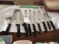 Full view of the magnetic knife rack with eight knives arranged side by side and mounting screws in plastic bag