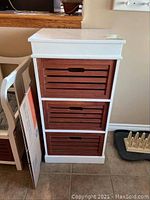 Front view of wooden storage unit with three dark brown crates in white frame