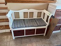 Full front view of white bench with gray cushion over three red crates
