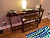 Image showing the sofa table with a matching side table placed underneath, on a hardwood floor, with various items arranged on top of the sofa table.