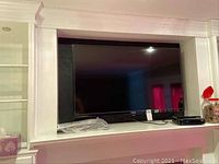 View of Toshiba television installed within a built-in wall recess with visible base stand and adjacent items.