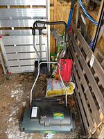 Full image of Yardworks electric dethatcher showing metal handle, control switch, motor casing, and wheels in storage area.