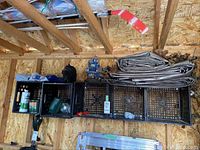 Wide shot showing two tarps folded on top of black milk crates, a snow shovel, garden watering can, and small garden statues including a blue tractor.