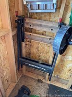 Frame of Black & Decker Work Mate Bench in corner with wear, showing lifting mechanism, black metal strips, and mounted round handle.