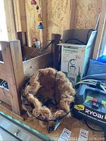 Metal hanging basket with coco matting liner, showing wear and use.