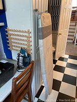 Ironing board standing upright with padded cover visible.