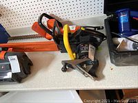 Photo showing WEN electric chainsaw with 14 inch bar and chain, orange and black with protective guard, placed on a white surface.