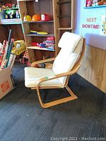 Side angle view of the wooden framed chair with white padded cushion showing the overall shape and structure.