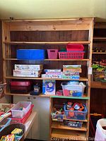 Full display of wood shelving with multiple plastic baskets, various boxed children's games including Crazy 8 Puzzles, and bins with toys and Play Doh.