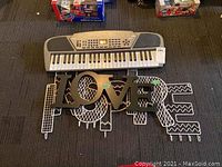 Electronic keyboard with built-in controls and keys, placed above the metal LOVE sign