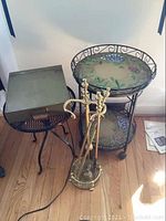 Full view of round serving tables, file box, and brass fireplace tools on hardwood floor