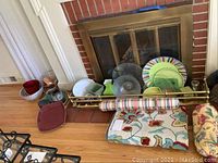 Full view of the area rug on the floor with two striped roll pillows, serving platters and plates placed beside it, along with some pillows and a fireplace screen in the background.