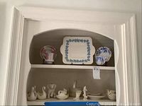 Shelf display including Wedgwood teacups and saucers, Wedgwood square plate with blue garland, and multiple Lenox porcelain animal figurines and small dishes