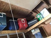 Shelf with multiple coolers in blue, red, white, and green colors, plus other items on the side