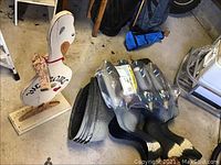 Wooden goose-shaped Welcome yard sign with orange beak and feet on base next to unpackaged and packaged plastic decoys.