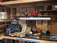Workbench and wooden shelves with books, vise, fish cleaning tools, hardware bins, and other workshop items.