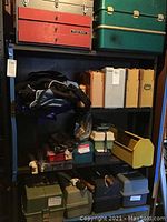 Two shelves displaying multiple tackle boxes, a duffel bag and small boxes of lures