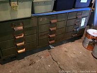Front view of full cabinet showing 12 green metal drawers with brass-tone handles