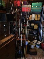 Fishing rods displayed in a wooden spinning stand, showing multiple rods with various handle materials.