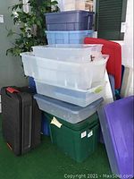 Overview of stacked storage totes and lids of various colors and sizes showing condition and assortment