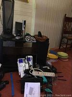 Overall lot setup showing a variety of electronics, fans, and accessories arranged near a shelf and the wall.