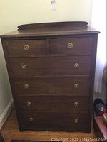 Front view of six drawer dresser with brass handles showing overall wear and nicks.