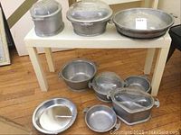Overview of eight pieces of Guardian aluminum cookware including four metal bowls and five glass lids.