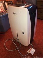 Full view of white and black Whirlpool dehumidifier with power cord coiled in front.