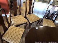Group photo showing four wooden dining chairs with gold diamond upholstery around a table.