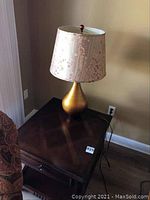 Photo showing the gold coke red lamp with shade placed on the Broyhill end table, highlighting overall appearance and color.