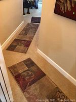 Photo showing the two Oriental Weavers floor runners and the dark brown rubber-backed floor mat placed in a hallway, highlighting sizes and patterns of the rugs and mat.