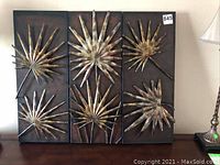 Front view of three metal wall art panels arranged side by side showing copper and brass sunburst designs on dark backgrounds.
