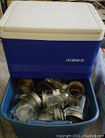 Photo of a blue Legend 12-can cooler with white lid and a blue plastic tote filled with empty glass jam jars and metal screw-on lids.