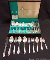 Open flatware storage case with turquoise interior and black exterior, showing slots of knives, forks, spoons.